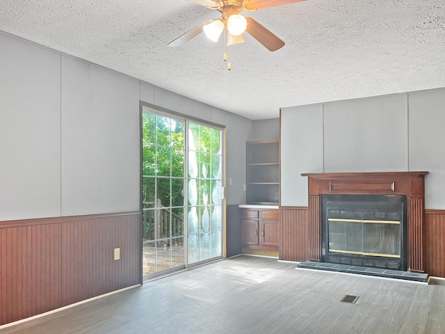 4112 Quail Farm Rd, Thomson, GA 30824 - unfurnished living room featuring ceiling fan, a textured ceiling, visible vents, wainscoting, and a glass covered fireplace