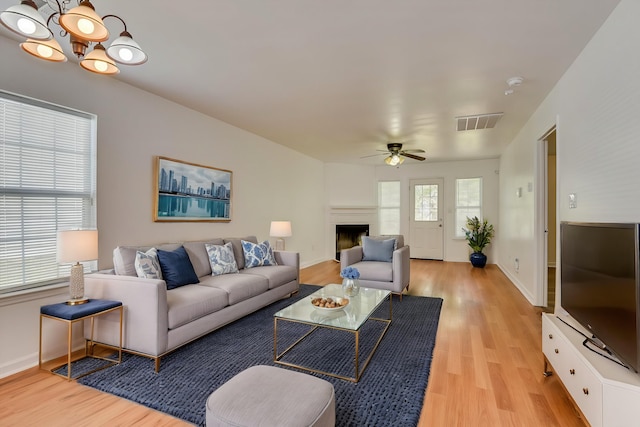 living room with light hardwood / wood-style floors and ceiling fan with notable chandelier