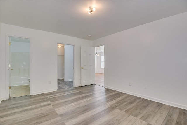 unfurnished bedroom with a walk in closet, light hardwood / wood-style flooring, ensuite bath, and a closet