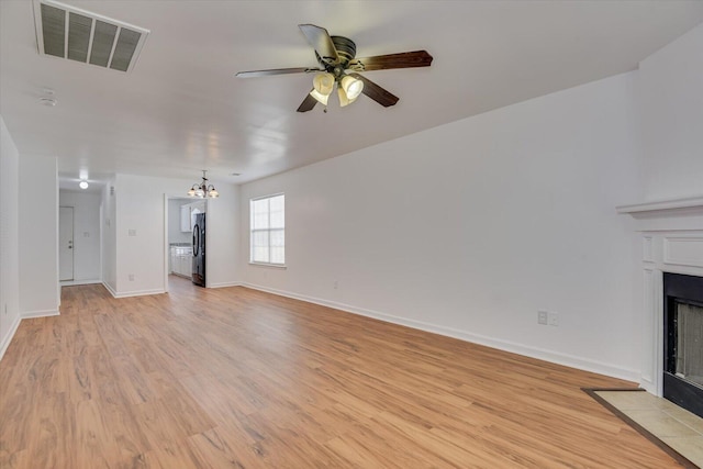 unfurnished living room with light hardwood / wood-style flooring and ceiling fan with notable chandelier