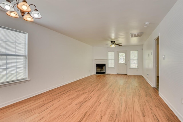 unfurnished living room featuring ceiling fan with notable chandelier and light wood-type flooring