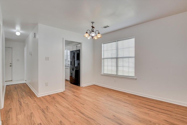 unfurnished room featuring light hardwood / wood-style floors and an inviting chandelier