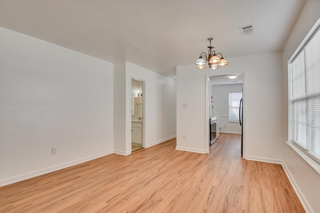 empty room featuring light hardwood / wood-style flooring and a chandelier