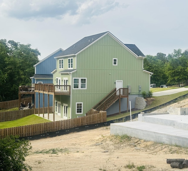 back of property with fence, roof with shingles, board and batten siding, and a deck