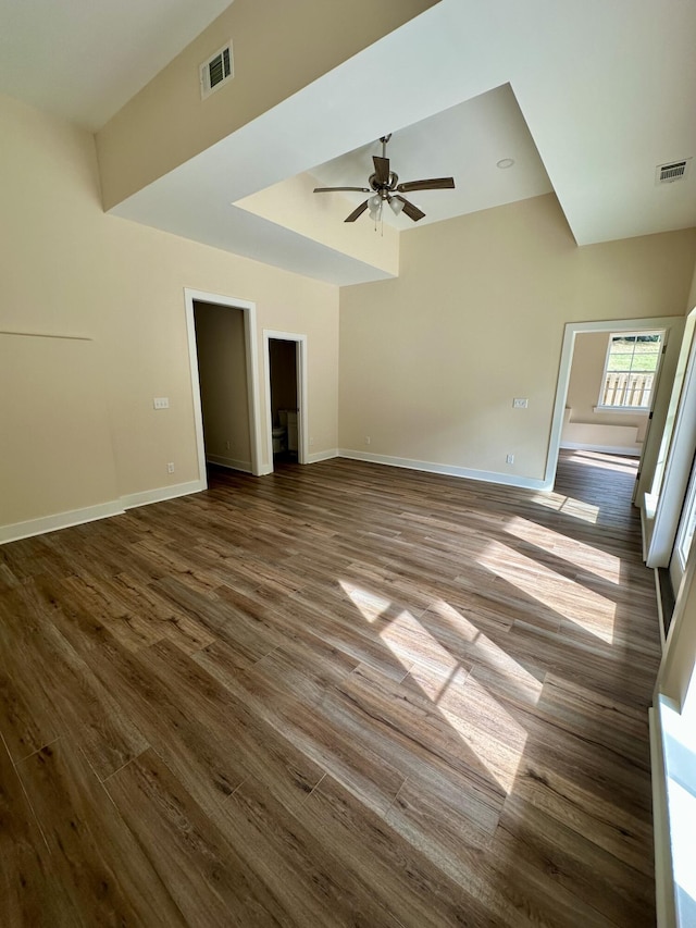 unfurnished living room with baseboards, a ceiling fan, dark wood-style floors, and visible vents