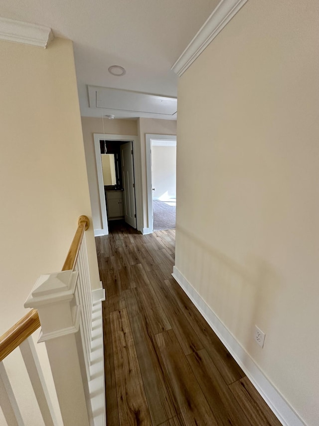hallway with attic access, dark wood finished floors, baseboards, an upstairs landing, and ornamental molding