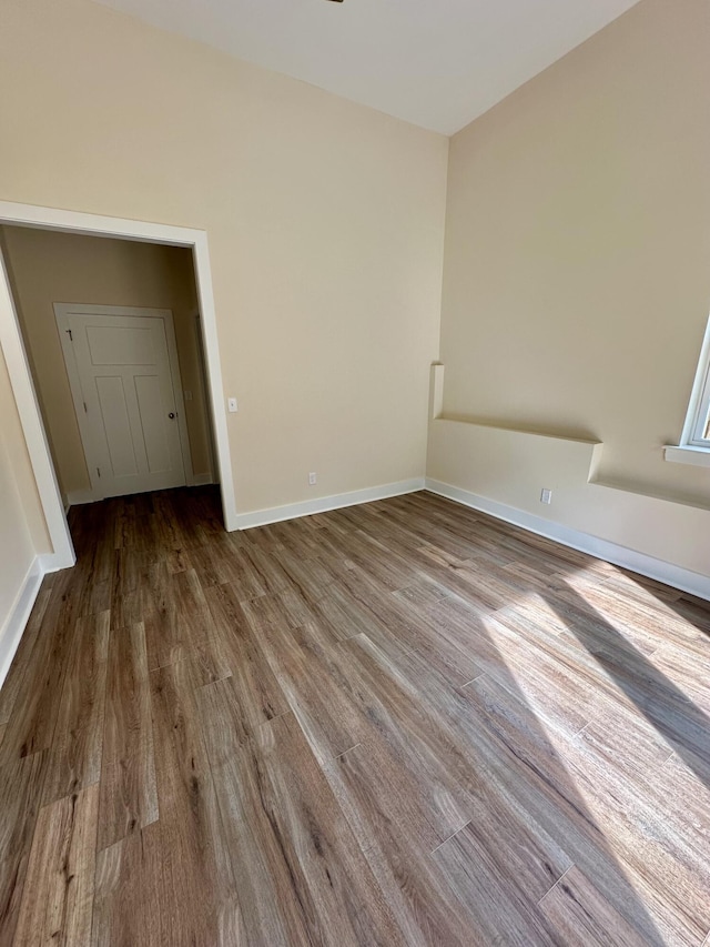 unfurnished room with baseboards and wood finished floors