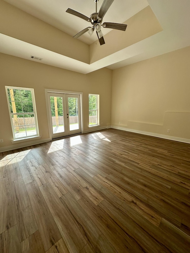spare room with a ceiling fan, visible vents, a healthy amount of sunlight, and dark wood finished floors