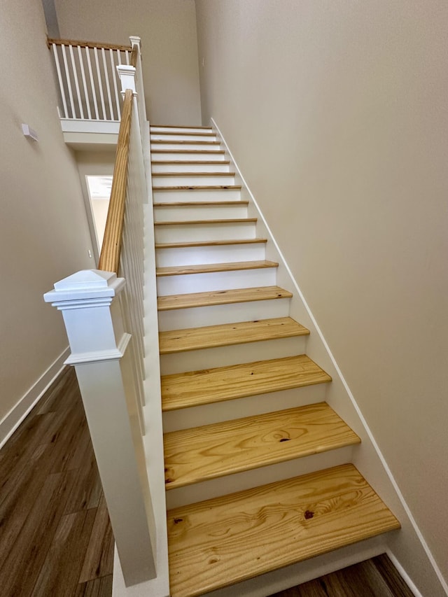 staircase with baseboards and wood finished floors