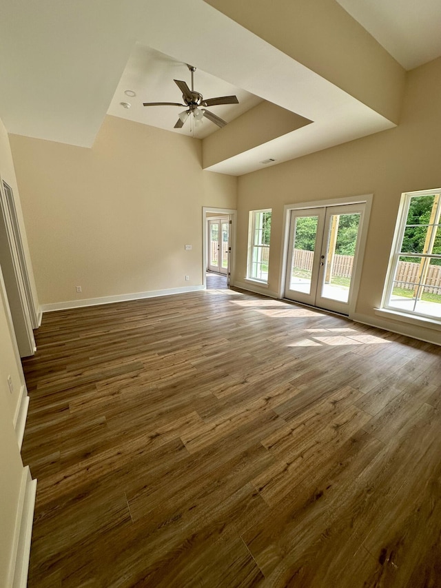 unfurnished living room with baseboards, dark wood-style flooring, a ceiling fan, and french doors