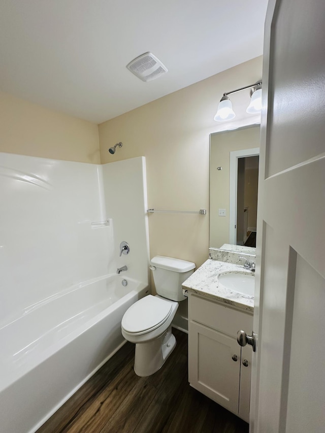 full bath with visible vents, wood finished floors, vanity, toilet, and tub / shower combination