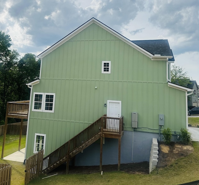 rear view of property featuring stairs, roof with shingles, and a deck
