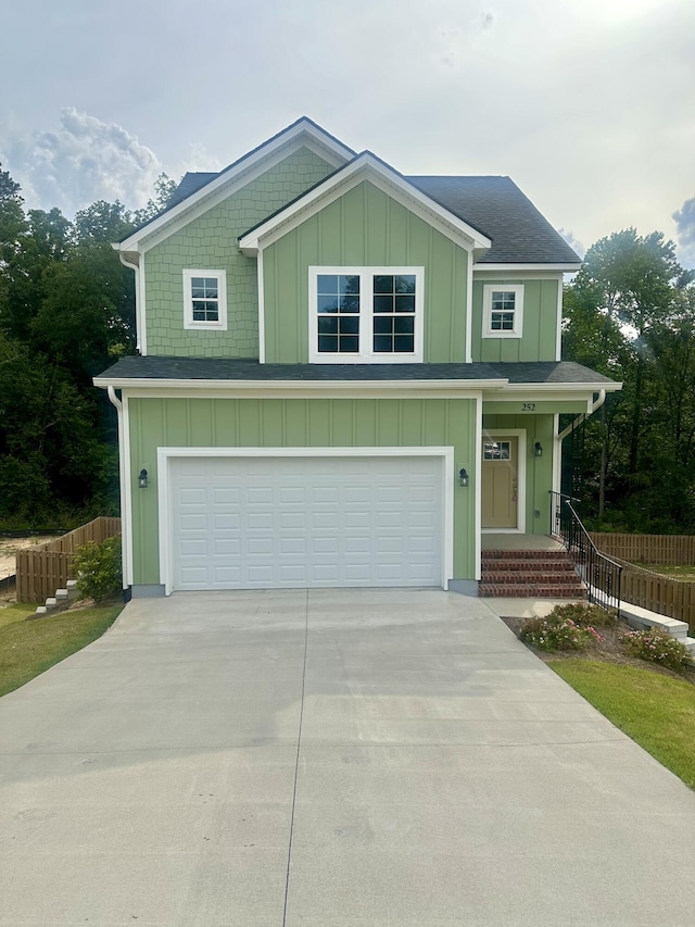 view of front of property featuring fence, board and batten siding, an attached garage, and driveway