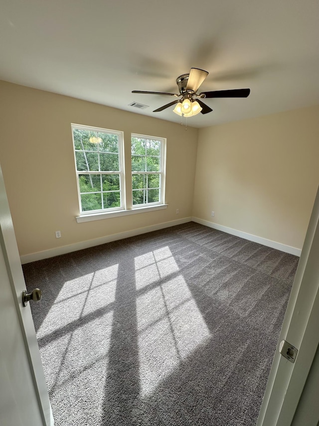 empty room featuring baseboards, ceiling fan, dark carpet, and visible vents