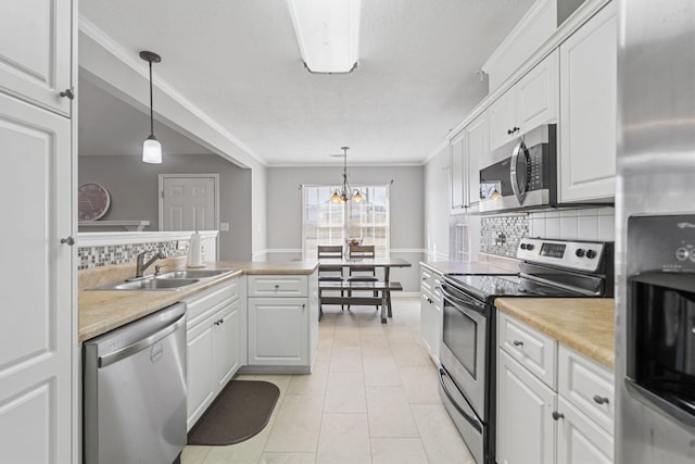 kitchen with white cabinetry, hanging light fixtures, crown molding, and stainless steel appliances