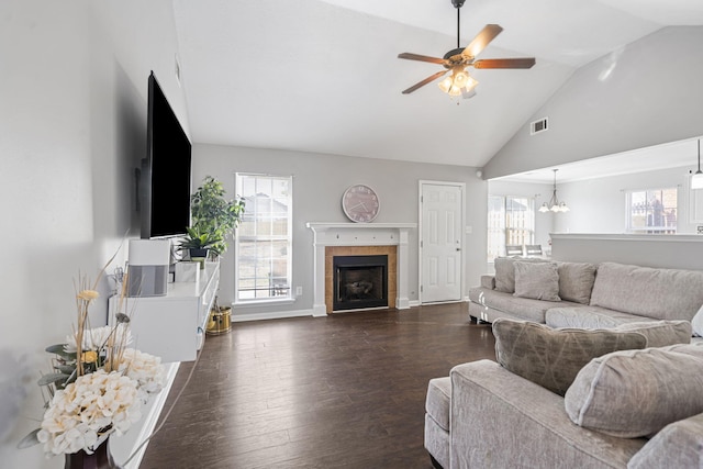 living room with high vaulted ceiling, ceiling fan with notable chandelier, a tile fireplace, and dark hardwood / wood-style floors