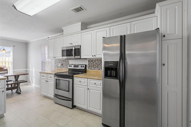 kitchen with white cabinetry, light tile patterned floors, ornamental molding, stainless steel appliances, and backsplash