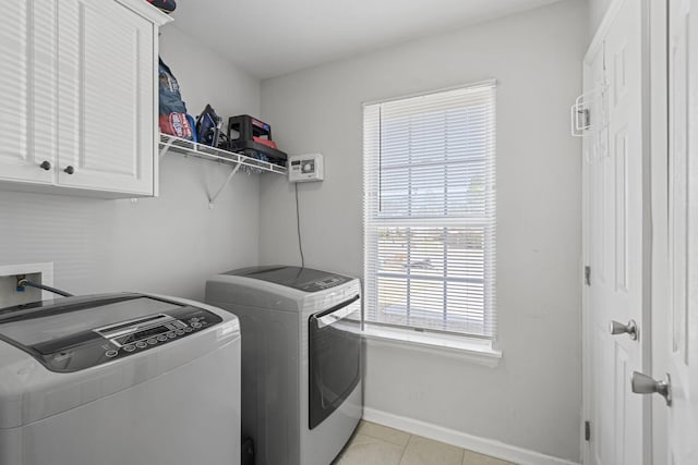 laundry room featuring washer and dryer, light tile patterned floors, and cabinets