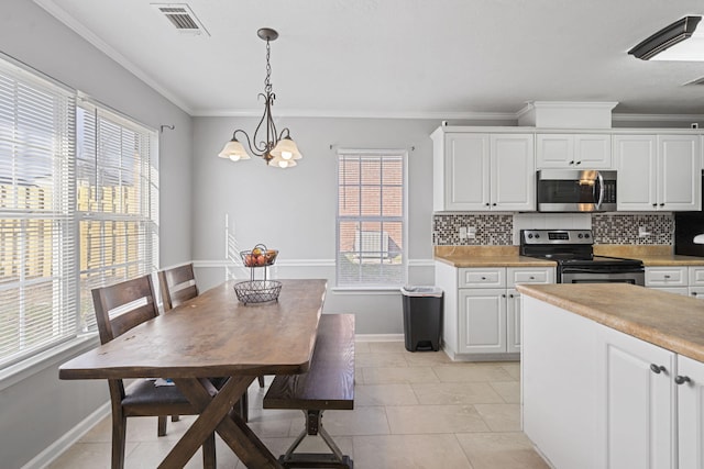 kitchen with stainless steel appliances, tasteful backsplash, hanging light fixtures, and white cabinets