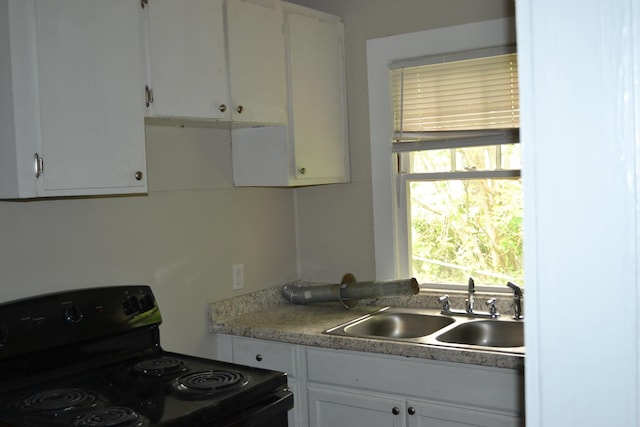 1919 Warren St, Augusta, GA 30904 - kitchen with black electric range oven, a sink, white cabinetry, and light countertops