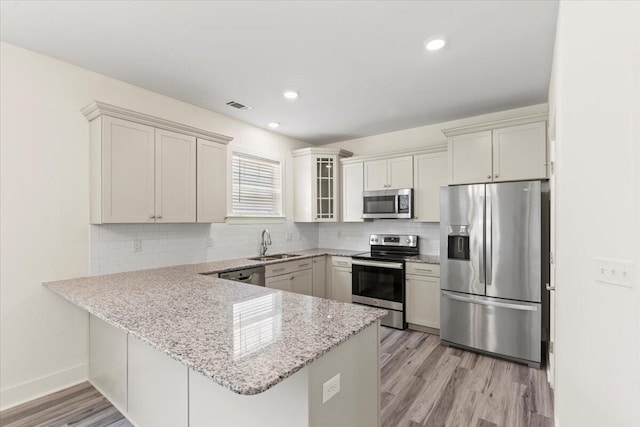 1404 Feldspar Ct, Augusta, GA 30909 - kitchen with appliances with stainless steel finishes, a peninsula, light wood-style floors, decorative backsplash, and recessed lighting