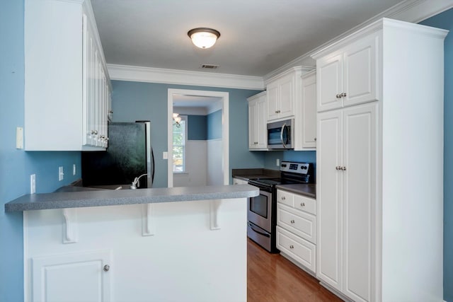 1102 Highmoor Ln, Evans, GA 30809 - kitchen with stainless steel appliances, a peninsula, a breakfast bar area, white cabinetry, and dark wood-style flooring