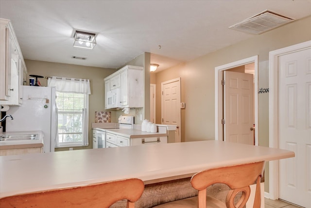 8030 Reagan Cir, Augusta, GA 30909 - kitchen with stove, white microwave, a kitchen bar, and white cabinetry