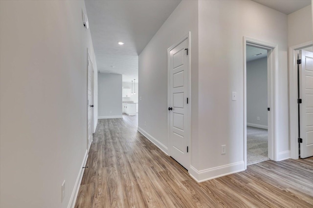 corridor featuring light wood-type flooring, baseboards, and recessed lighting