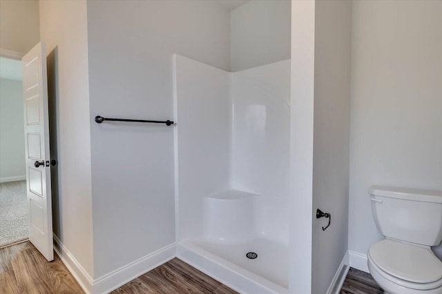 full bathroom featuring a shower, baseboards, toilet, and wood finished floors