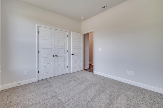 unfurnished bedroom featuring a closet, carpet, visible vents, and baseboards