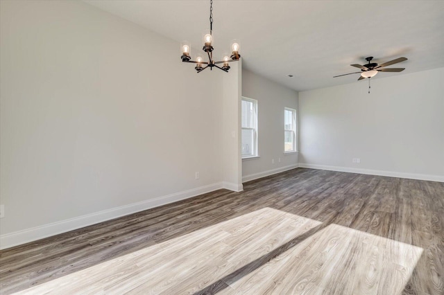 unfurnished room featuring ceiling fan with notable chandelier, wood finished floors, and baseboards