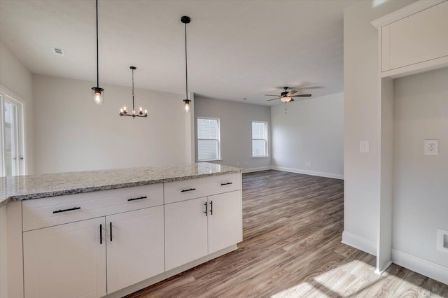 kitchen with white cabinetry, light wood-style flooring, baseboards, and light stone counters