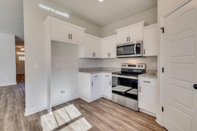 kitchen with appliances with stainless steel finishes, white cabinetry, and light wood-style floors