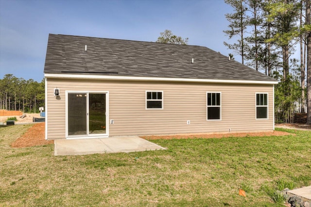 rear view of house featuring roof with shingles, a lawn, and a patio