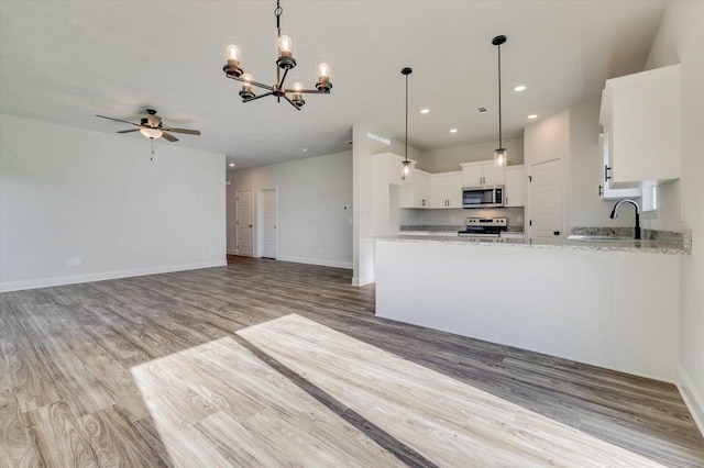 kitchen with recessed lighting, appliances with stainless steel finishes, white cabinets, light stone countertops, and light wood-type flooring