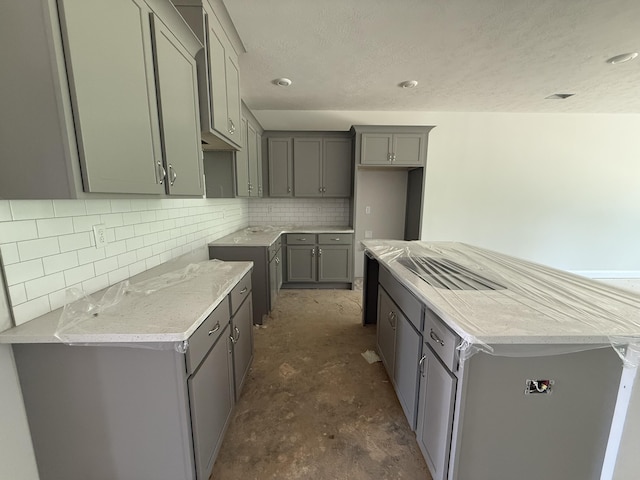 1141 Clareton Dr, Grovetown, GA 30813 - kitchen with gray cabinetry, concrete flooring, decorative backsplash, a center island, and a textured ceiling