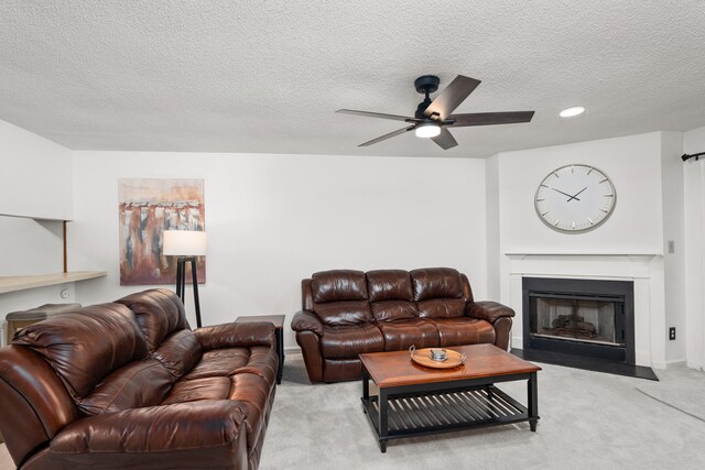 carpeted living room with ceiling fan and a textured ceiling