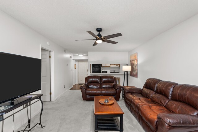 living room with a textured ceiling, light colored carpet, and ceiling fan