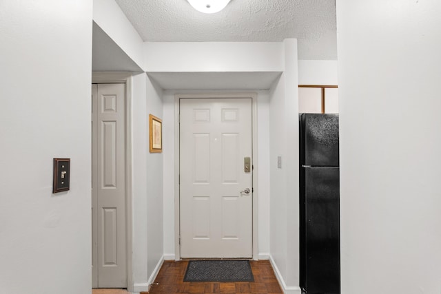 doorway to outside featuring dark parquet flooring and a textured ceiling