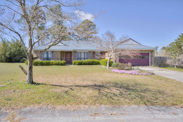 ranch-style home with driveway, a garage, metal roof, and a front yard