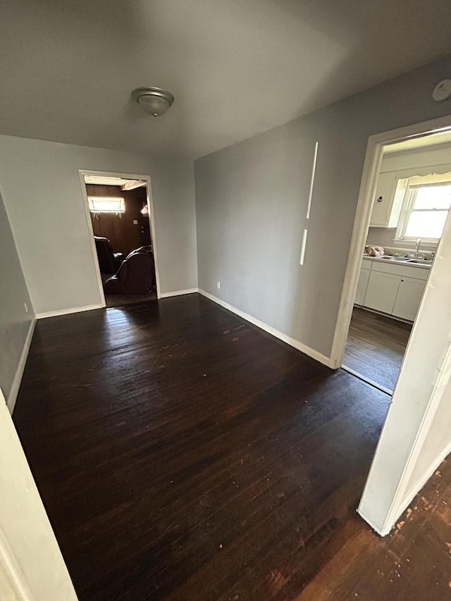 interior space with dark wood-style flooring, a sink, and baseboards