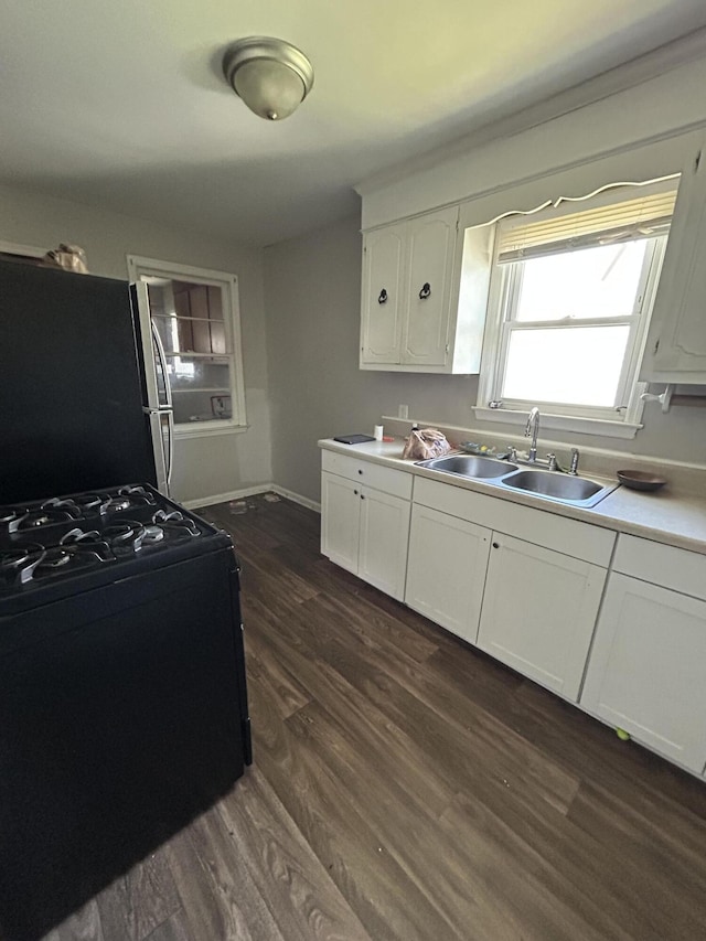 kitchen with freestanding refrigerator, white cabinets, light countertops, and a sink