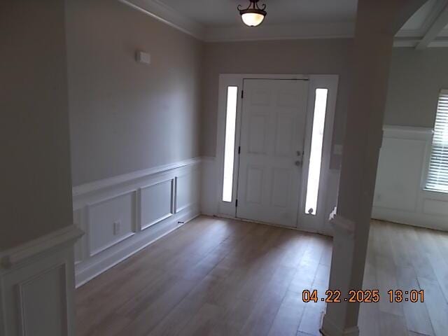foyer entrance featuring wood finished floors, beamed ceiling, a decorative wall, and a wainscoted wall