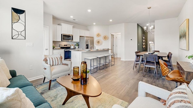 living room with sink, a chandelier, and light hardwood / wood-style flooring