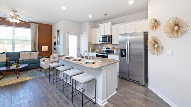 kitchen featuring sink, a breakfast bar area, a center island with sink, stainless steel appliances, and white cabinets