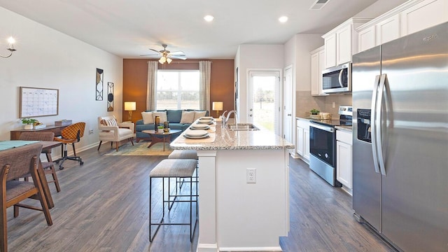 kitchen with sink, a breakfast bar, white cabinetry, stainless steel appliances, and an island with sink