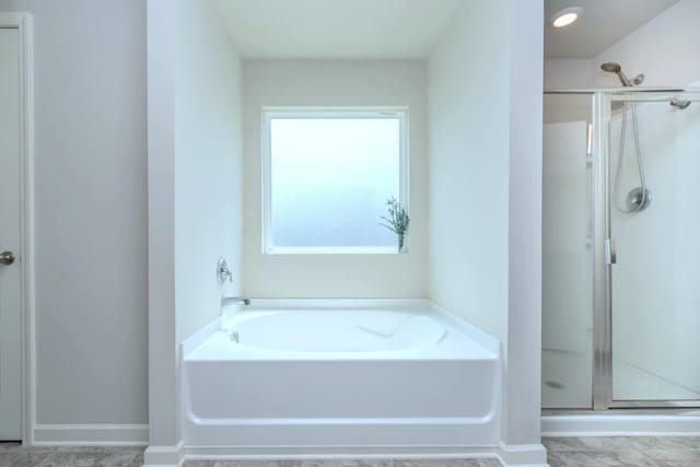 bathroom with a stall shower and a garden tub