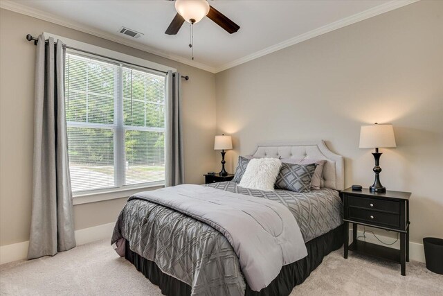 carpeted bedroom featuring ceiling fan, ornamental molding, and multiple windows