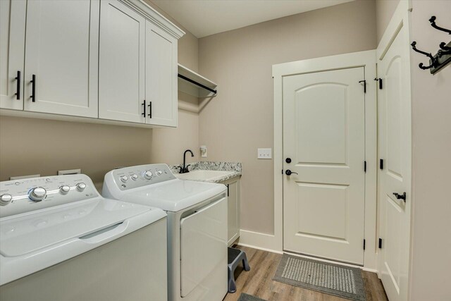 laundry room with light hardwood / wood-style floors, cabinets, separate washer and dryer, and sink