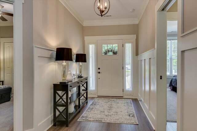 entryway with crown molding, dark hardwood / wood-style flooring, and ceiling fan with notable chandelier